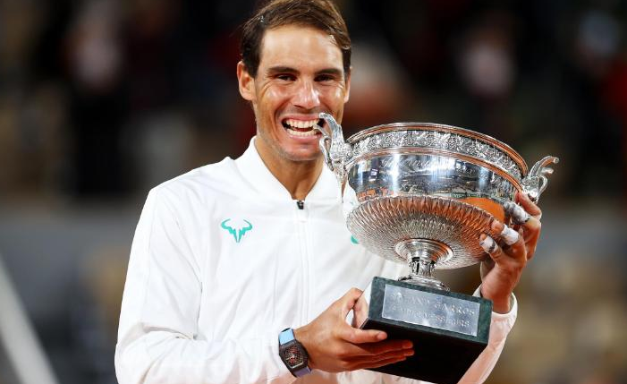 Rafael Nadal bites the winning trophy after claiming the French Open title for the 13th time time with a straight sets victory over Novak Djokovic.