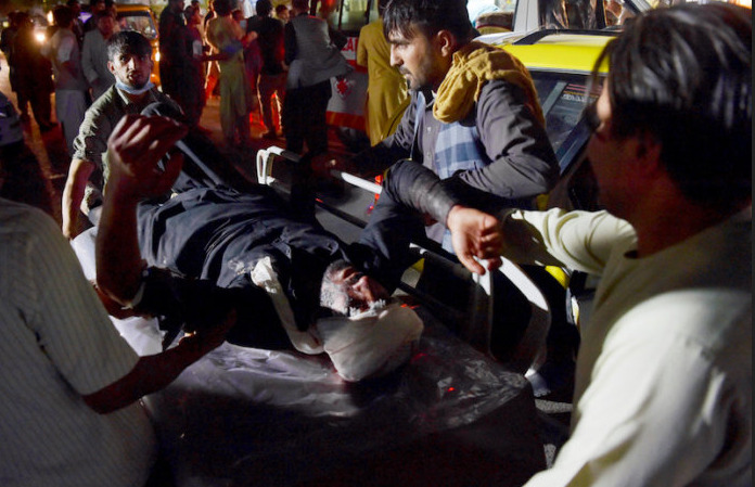 Medical and hospital staff bring an injured man on a stretcher for treatment after two blasts, which killed at least five and wounded a dozen, outside the airport in Kabul on August 26, 2021.